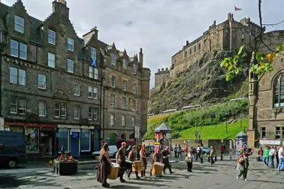 a group of people walking down a street in front of buildings at JOIVY Bohemian Writers Retreat in Old Town in Edinburgh