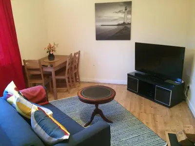 a living room with a blue couch and a tv at Ardminish House Gigha in Isle of Gigha