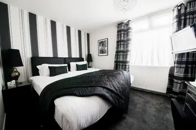 a black and white bedroom with a bed and a window at The Burnside Hotel in Glasgow