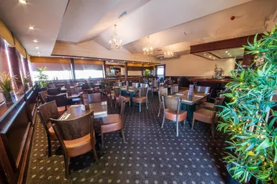 a restaurant with wooden tables and chairs and plants at The Burnside Hotel in Glasgow