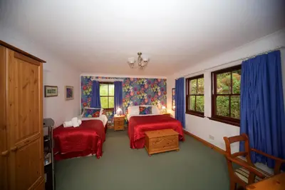 a bedroom with two beds and blue curtains at Craigard House Hotel in Campbeltown