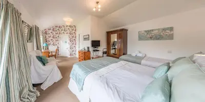a bedroom with a large white bed and a chair at Craigard House Hotel in Campbeltown