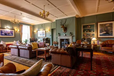 a living room with couches and a fireplace at Knipoch House Hotel in Oban
