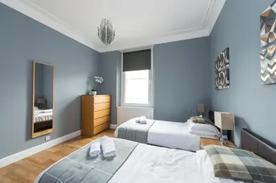 a blue bedroom with two beds and a mirror at Castle apt, modern, CENTRAL in Edinburgh