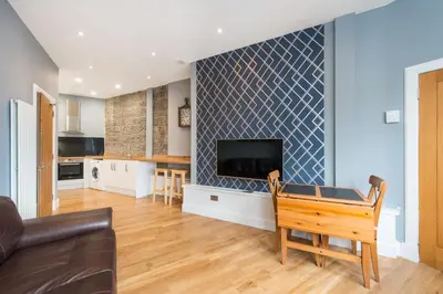 a living room with a couch and a tv on a wall at Castle apt, modern, CENTRAL in Edinburgh