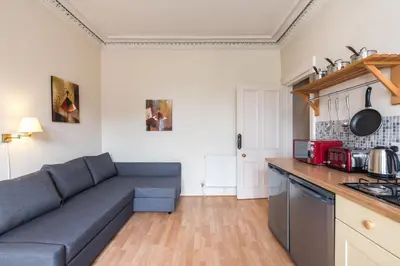 a living room with a blue couch in a kitchen at Spacious & Unique city central 1 bed with WiFi in Edinburgh