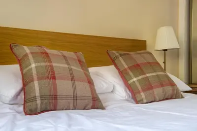 a bed with two plaid pillows on top of it at Charming 1 Bed Apartment with Castle View in Edinburgh