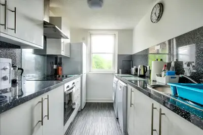 a large kitchen with white cabinets and a window at Charming 1 Bed Apartment with Castle View in Edinburgh