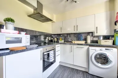 a kitchen with white cabinets and a washer and dryer at Stunning Studio Apartment Castle View in Edinburgh