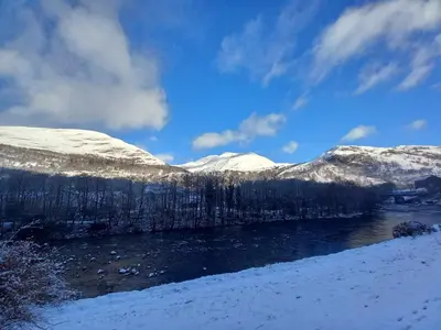 a river with snow covered mountains in the background at Nevis Pod, West Highland Way Holidays in Kinlochleven