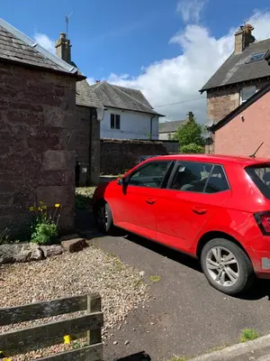 a red car parked in front of a house at The Grey Cottage in Blackford