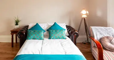 a bedroom with a bed with blue and white pillows at Clyde View Apartment in Helensburgh