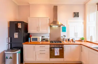 a kitchen with white cabinets and a black refrigerator at Clyde View Apartment in Helensburgh