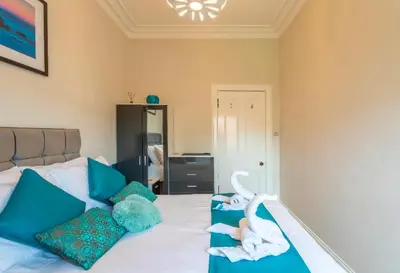 a bedroom with a bed with blue pillows and swans on it at Clyde View Apartment in Helensburgh