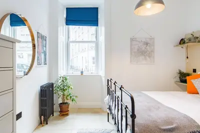 a bedroom with a bed and a mirror at The Plywood Flat, Modern Style In A Traditional Tenement in Edinburgh