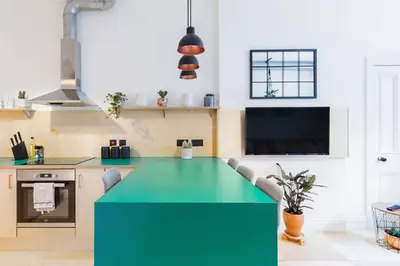a green island in a kitchen with a tv at The Plywood Flat, Modern Style In A Traditional Tenement in Edinburgh