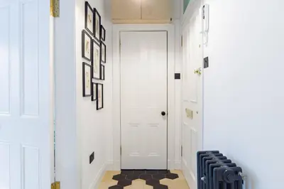 a hallway with a white door and a checkered floor at The Plywood Flat, Modern Style In A Traditional Tenement in Edinburgh