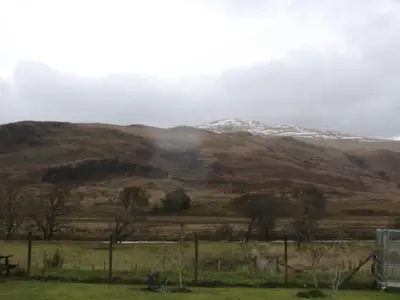 a field with a snow covered mountain in the distance at Luib Hotel in Killin