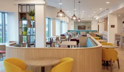 a restaurant with tables and chairs and a cafeteria at Hampton By Hilton Edinburgh Airport in Ingliston