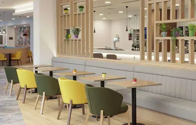 a restaurant with wooden tables and yellow chairs at Hampton By Hilton Edinburgh Airport in Ingliston