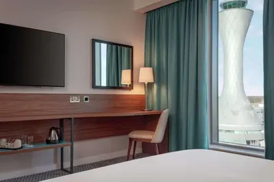 a hotel room with a desk with a television and a window at Hampton By Hilton Edinburgh Airport in Ingliston