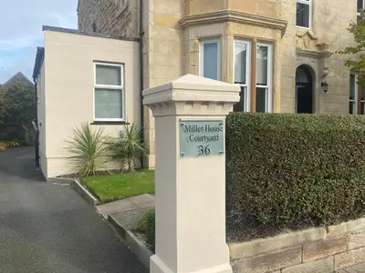 a white house with a sign in front of a house at Miller House Courtyard in Ayr