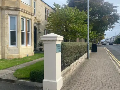 a white pillar on a sidewalk in front of a building at Miller House Courtyard in Ayr