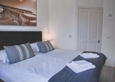 a bedroom with a white bed with towels on it at Miller House Courtyard in Ayr