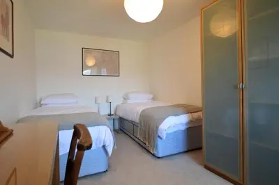 a bedroom with two beds and a desk and a table at Gate Cottage in Tighnabruaich