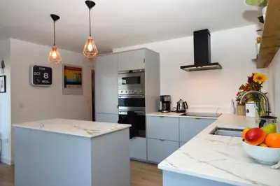 a kitchen with white cabinets and a bowl of fruit on the counter at Gate Cottage in Tighnabruaich