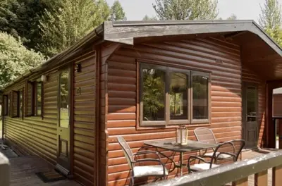 a cabin with a table and chairs on a deck at Caol Gleann Lodge in Rowardennan