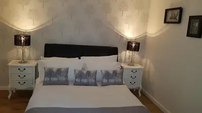 a bedroom with a bed with two night stands and two lamps at Largs stay With Private parking in Largs