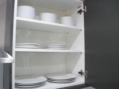 a cupboard filled with white plates and dishes at Westpark Apartment in East Kilbride