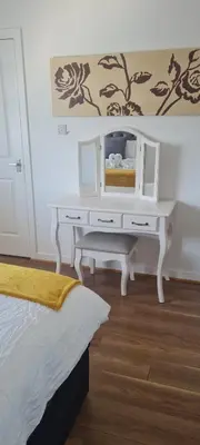 a bedroom with a white desk with a mirror at Silverburn new house with free parking and nice garden in Glasgow