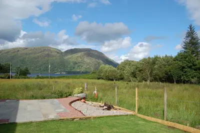 a fence in a field with mountains in the background at Ben View in Taynuilt