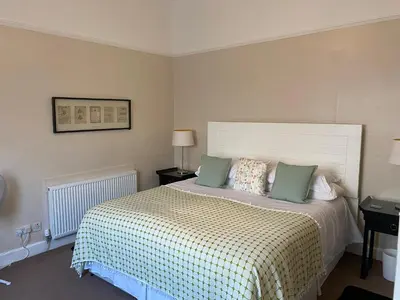a bedroom with a bed with green pillows at A Wee Cottage In Dunfermline in Dunfermline