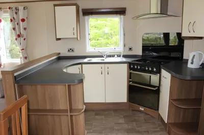 a kitchen with white cabinets and a black counter top at Glen View in Taynuilt