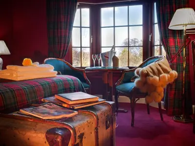 a bedroom with a bed and a table and a window at Champany Inn in Linlithgow
