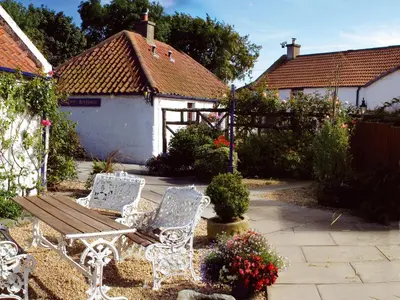 two white chairs and a bench in a garden at Champany Inn in Linlithgow