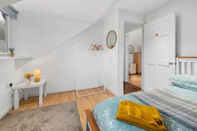 a white bedroom with a bed and a table at Beautiful 2BR Apartment with McCaigs Tower views in Oban