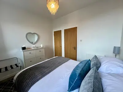 a bedroom with a large bed with blue pillows at Central Apartment Linlithgow in Linlithgow