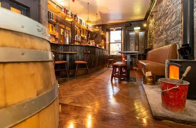 a room with a bar with wooden floors and a barrel at The Whisky Vaults in Oban