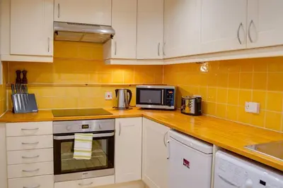 a kitchen with white cabinets and a microwave at JOIVY Warm & Welcoming Flat near Edinburgh Castle in Edinburgh