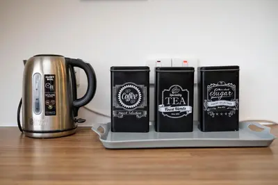 three coffee mugs on a tray next to a coffee pot at Stunning 2BR Loft Apt in Oban - Sea Views in Oban