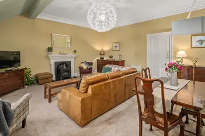 a living room with a couch and a table at Panoramic Sea Views - Stunning 3BD Apt & Balcony in Oban