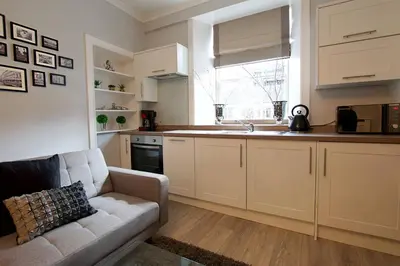 a living room with a couch and a kitchen at JOIVY Unique Old Town Stay under Edinburgh Castle in Edinburgh