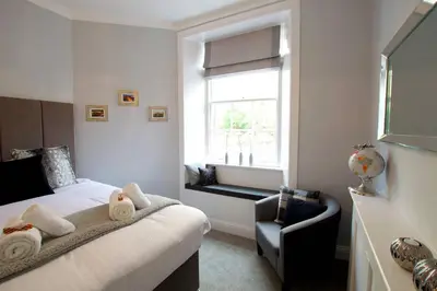 a bedroom with a bed and a chair and a window at JOIVY Unique Old Town Stay under Edinburgh Castle in Edinburgh