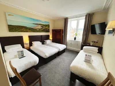 a hotel room with three beds and a window at Buccleuch Arms Hotel in Moffat