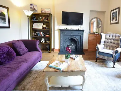 a living room with a purple couch and a fireplace at JOIVY Classic Apt with Castle Views in Old Town in Edinburgh