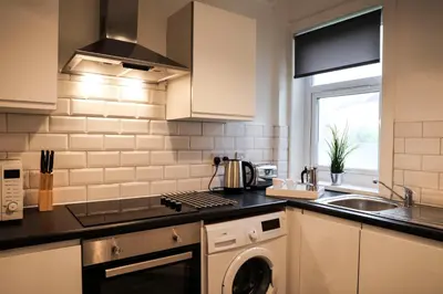 a kitchen with a washer and dryer in it at Baron View Apartment in Paisley